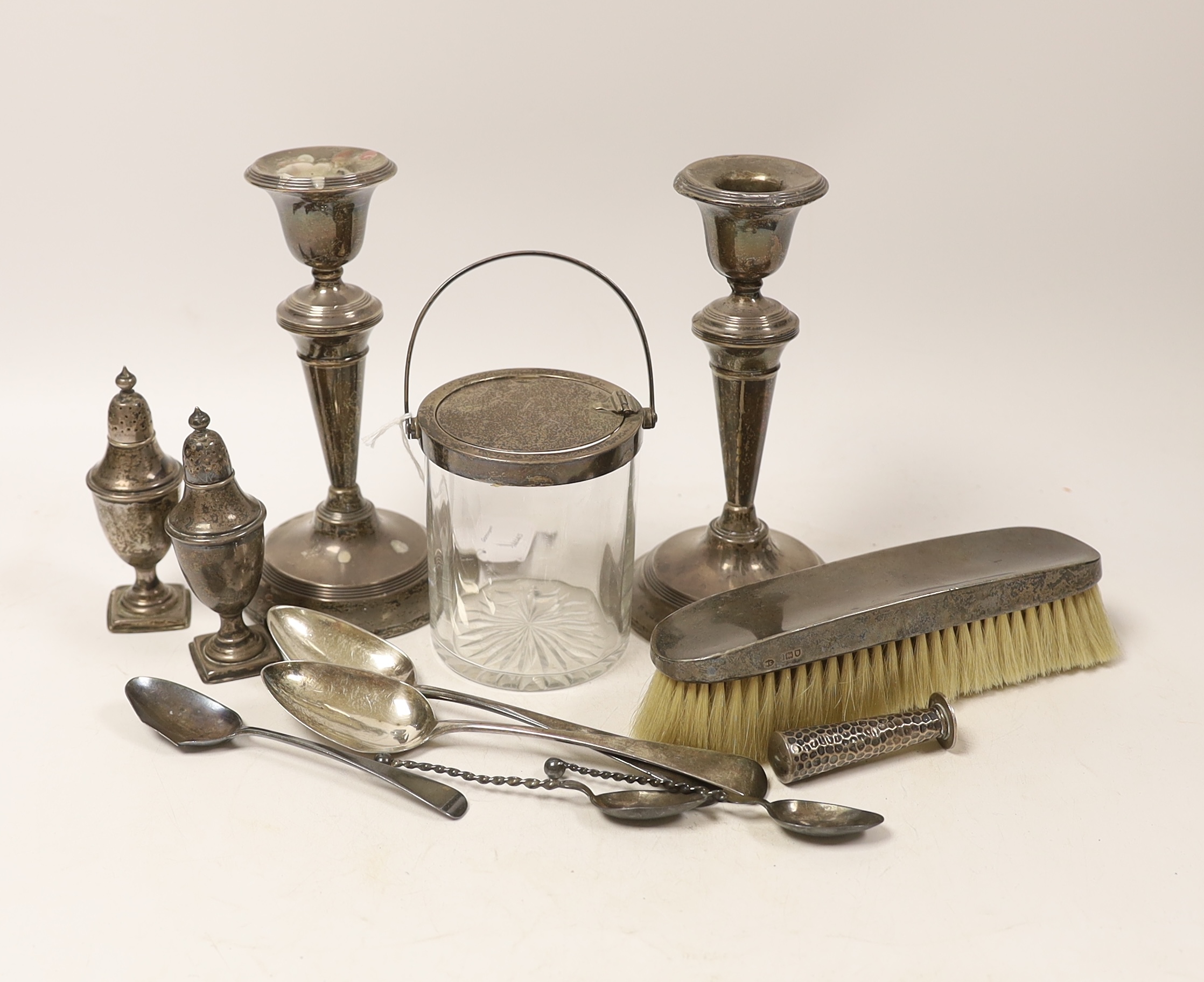Sundry silver, consisting of three pieces of George III flatware, two 800 standard coffee spoons, a pair of candlesticks(a.f.), a lidded glass preserve pot, clothes brush, two pepperettes and a desk seal.